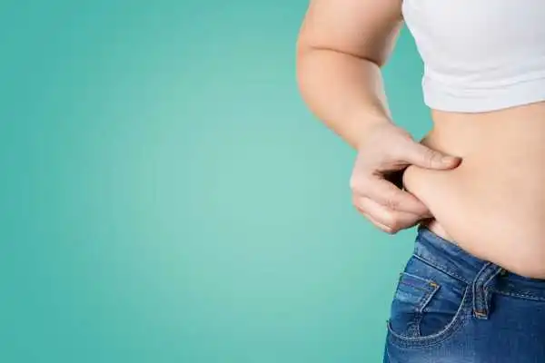 Image of woman pinching her love handles to show weight gain Leominster